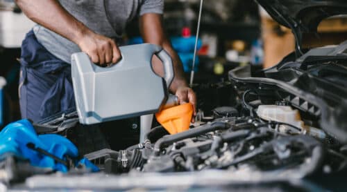 Closeup Garage Mechanic professional working car auto service engine oil filling up.