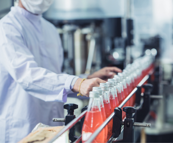 A person in a sanitary gown inspecting bottled products