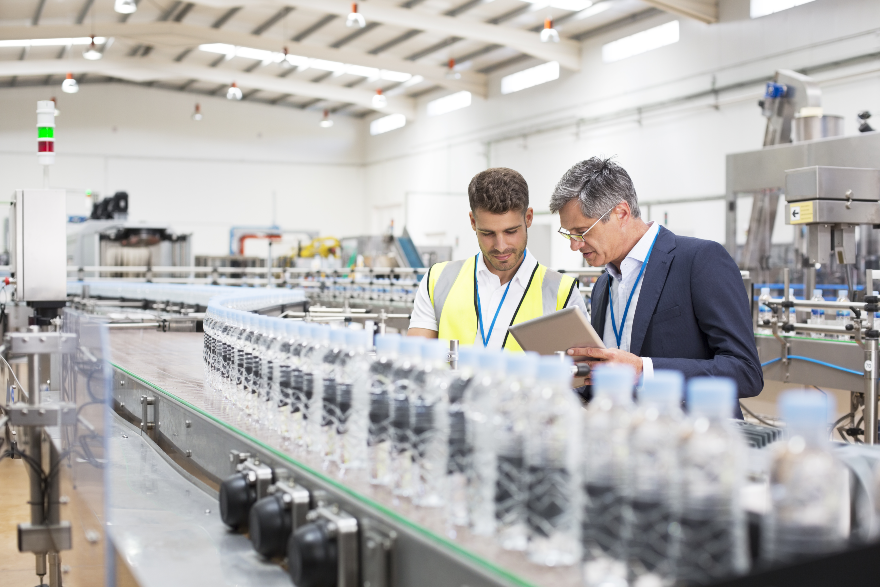 Two workers examine a production line up close.