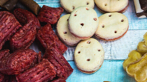 An array of dog treats arranged on a a wood surface.