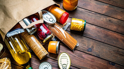 An overflowing grocery bag of food items.