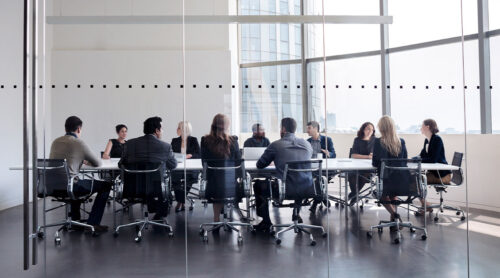 A row of workers sitting at a long conference table.