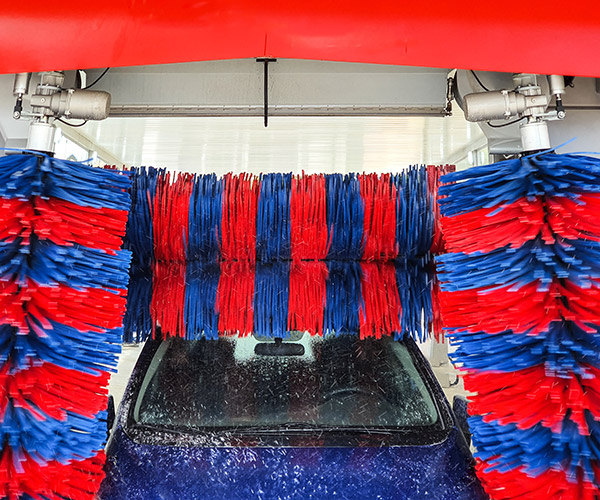 Car in car wash going through large brushes.