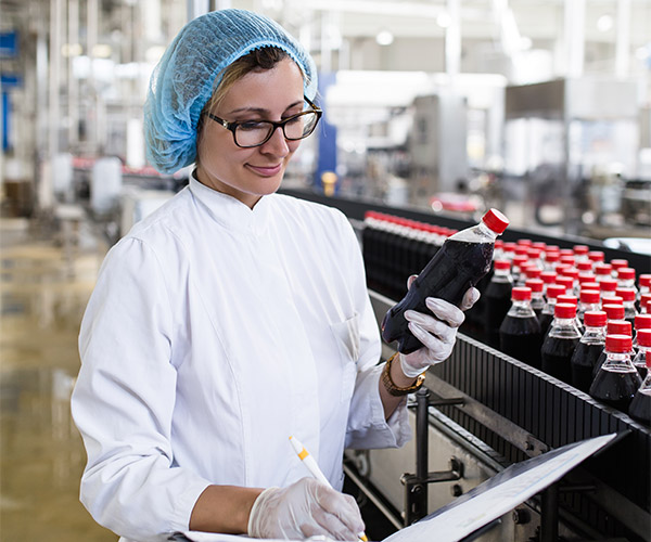 Woman inspecting beverages coming off production line.