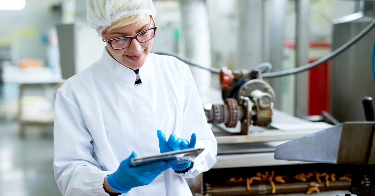 Women with tablet records updates on food quality control data in a processing plant. 