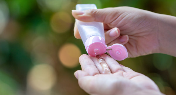 Woman using small bottle of hand sanitizer.