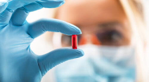 A lab tech examines a pill capsule.