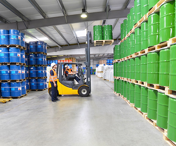 Moving green barrels with a fork truck.