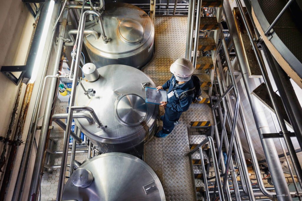 A factory worker overlooks vats