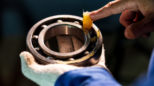 A technician uses an environmentally acceptable lubricant on ball bearings.