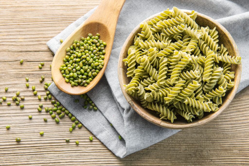 Pesto pasta sits prepared in a wooden bowl.